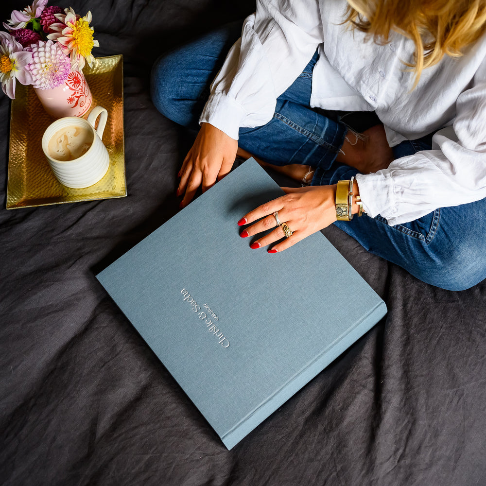 
                      
                        A lady sitting on a bed about to look through a large photo album
                      
                    