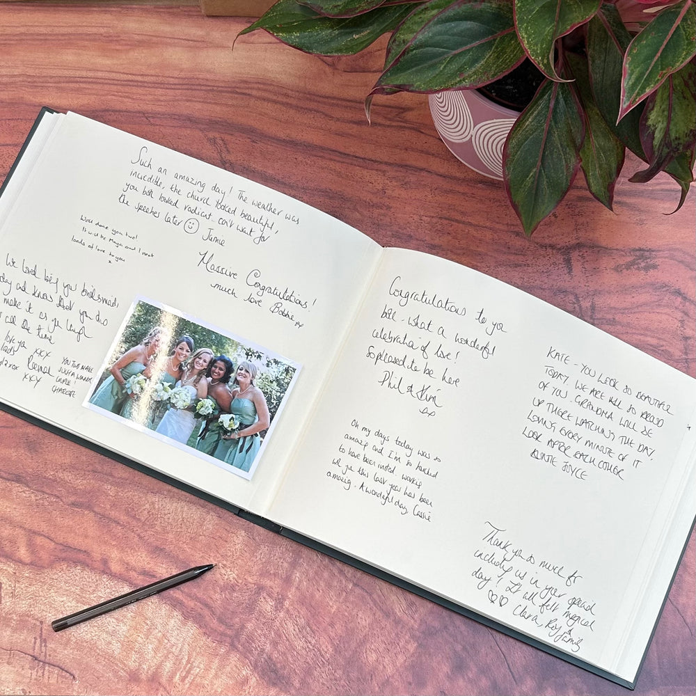 
                      
                        On a coffee table is an open wedding guest book with a pen. You can see all the written messages from guests inside and a photo. There is also a pen for people to sign the book.
                      
                    