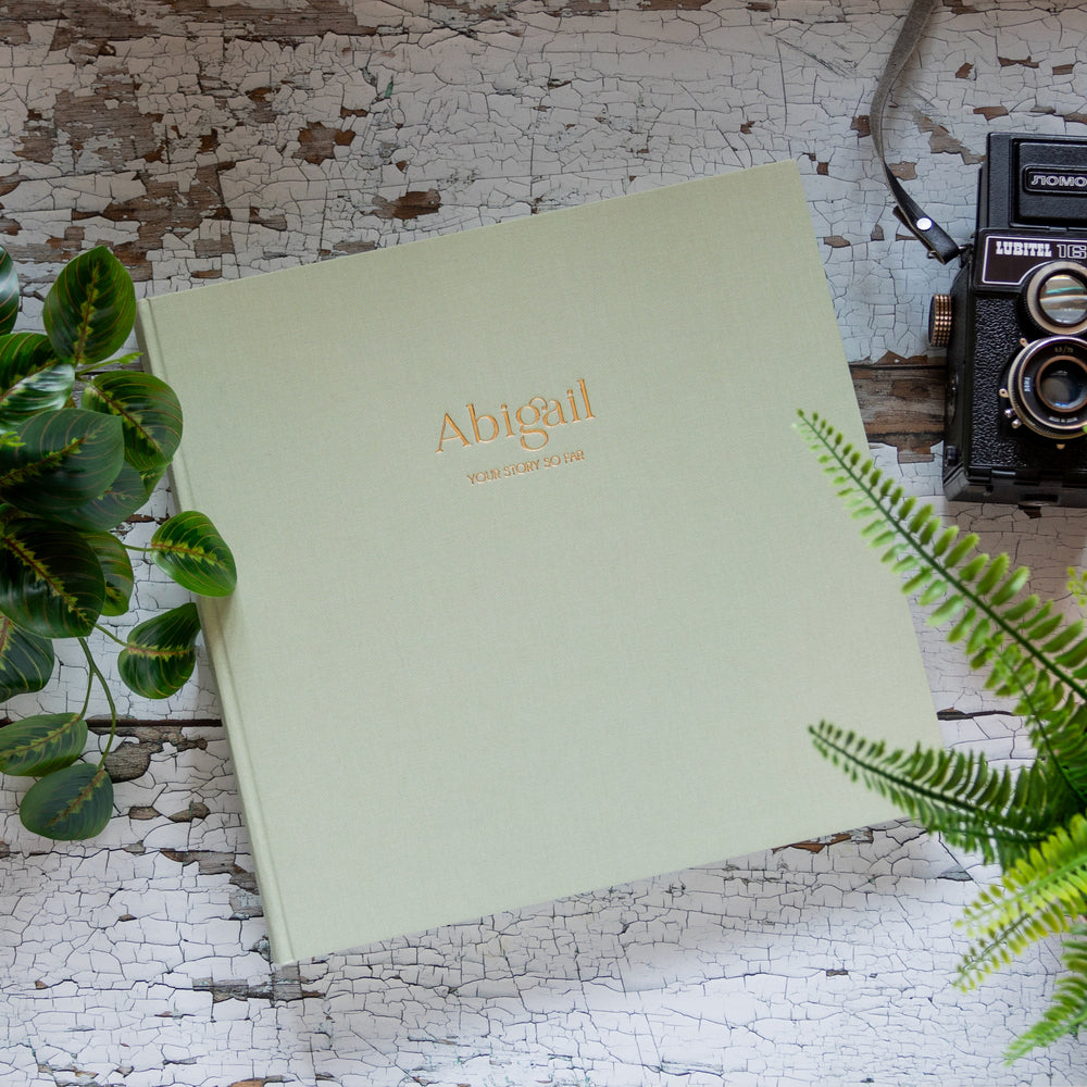 
                      
                        Beautiful personalised photo album with gold embossed title resting on a table
                      
                    