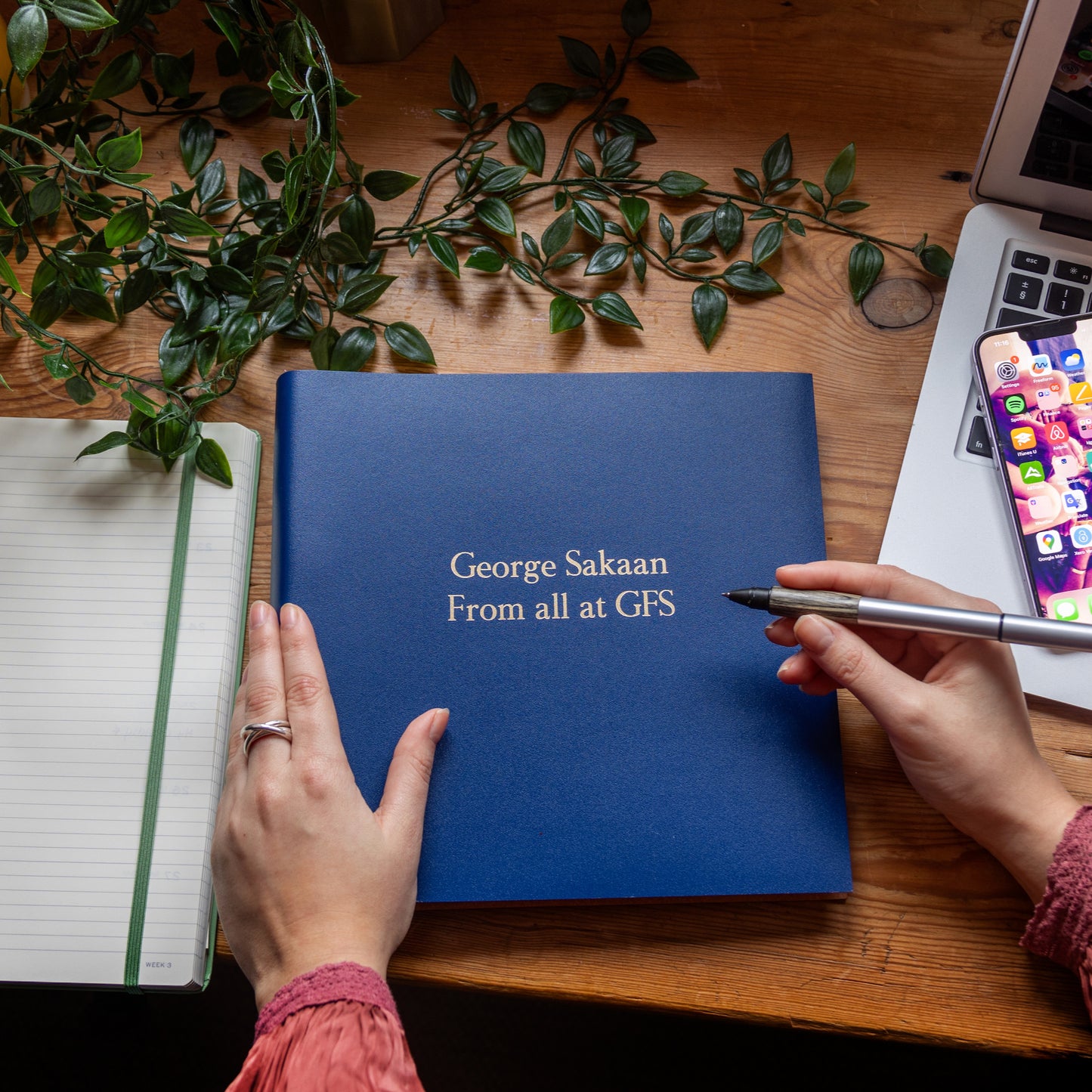 On a work desk is a leather retirement book that has been personalised on the front with gold lettering.