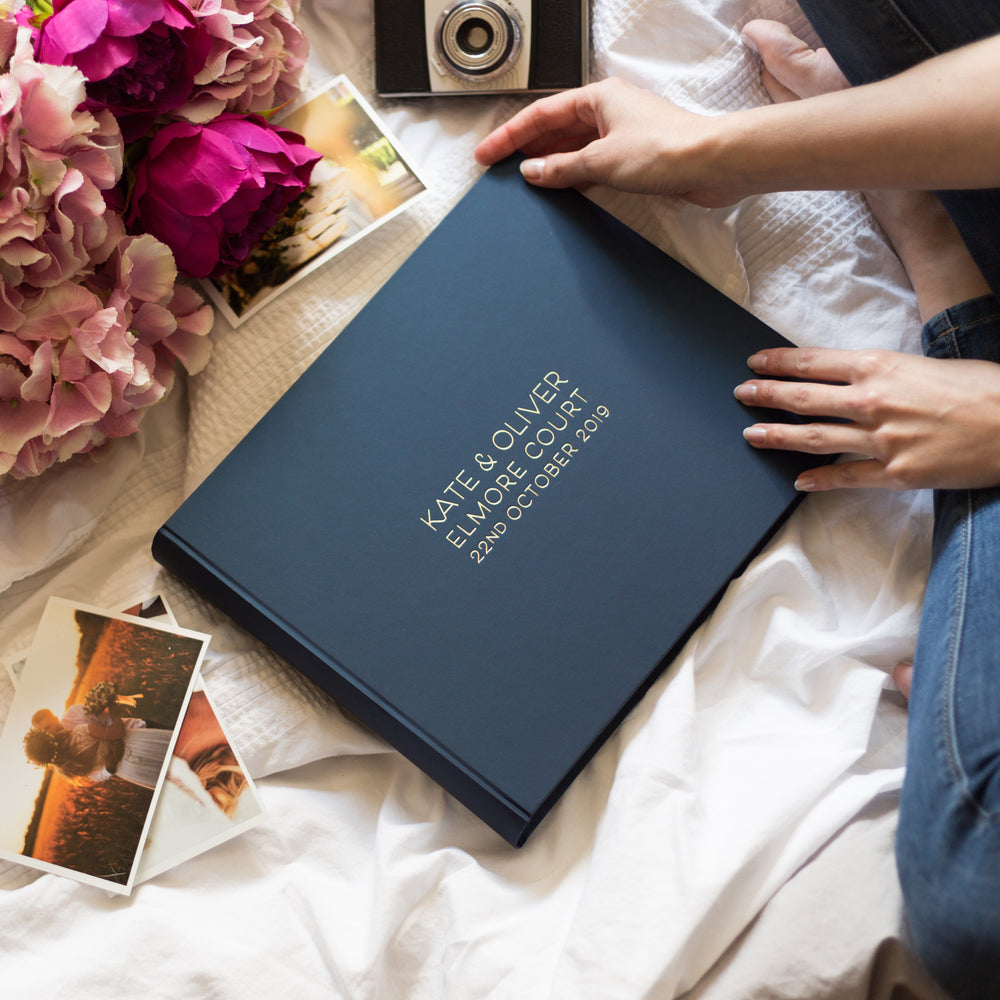 There is a woman who is about to fill her album with photographs. The dark blue opulent album has been personalised in gold hot foiling. 